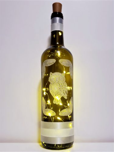 Bottle light with a lace owl and feathers