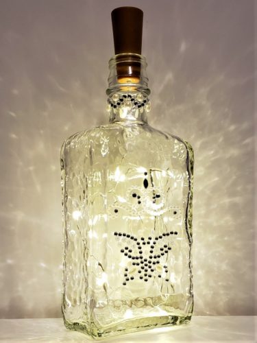 A mini bottle light with bevelled details, decorated with a pearl and jewel butterfly.