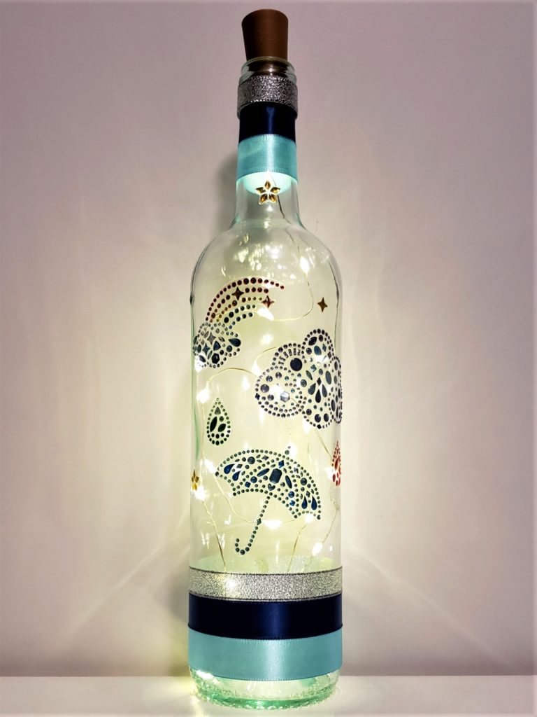 Bottle light with jewelled clouds, a rainbow, umbrella and raindrops.
