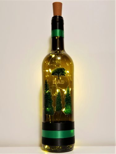 Father's Day bottle light with "Dad" surrounded by tall trees.