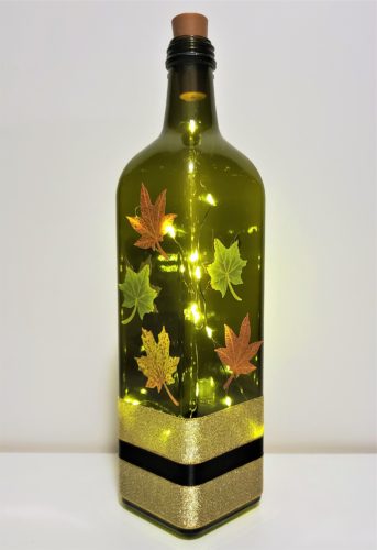 Bottle light with fall leaves on three sides of a four sided bottle.