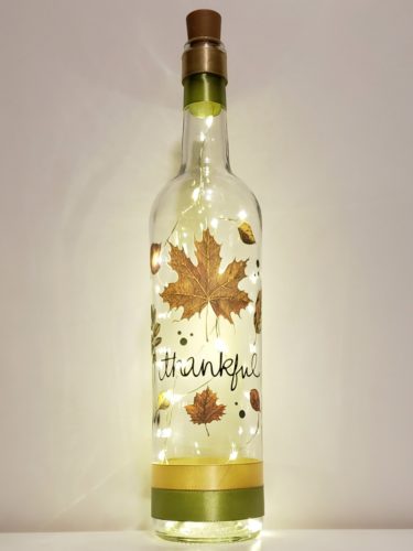 Bottle light with "Thankful" in cursive surrounded by realistic fall leaves.