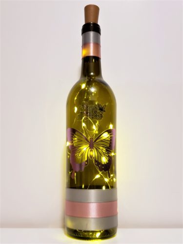 Bottle light with a large metallic butterfly and an outline of roses in silver.