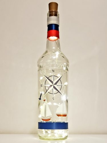 Bottle light with a compass and two sailboats.