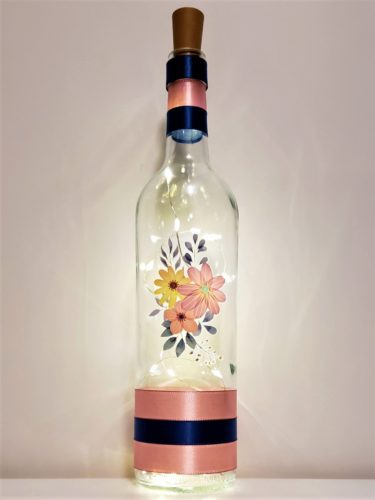 Bottle light featuring a waxy floral arrangement in rose, yellow and blue-grey tones.