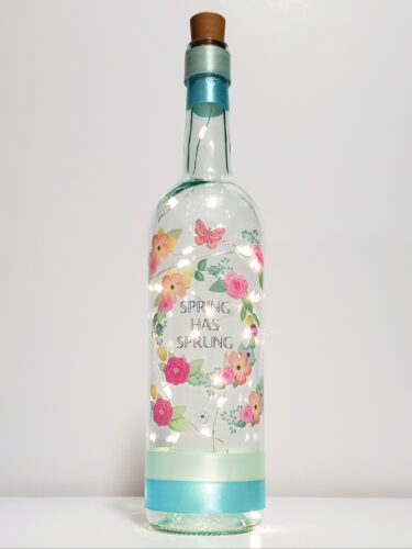 Bottle light with colourful flowers and "Spring has sprung" in the middle of a wreath.