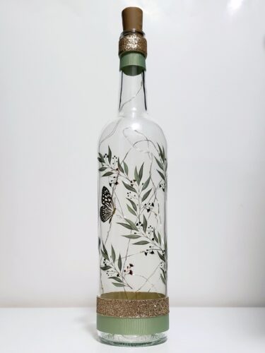 Bottle light with leaves and branches and a gold butterfly.