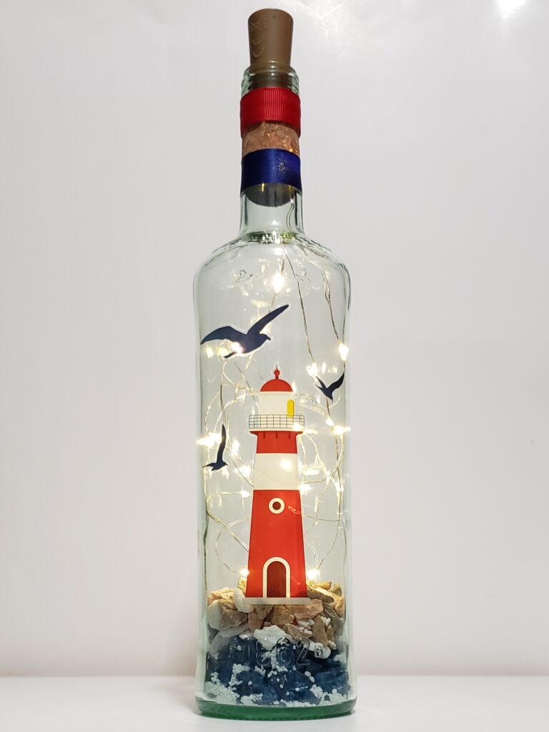 Lighthouse bottle light with crushed glass, white sand and stones.